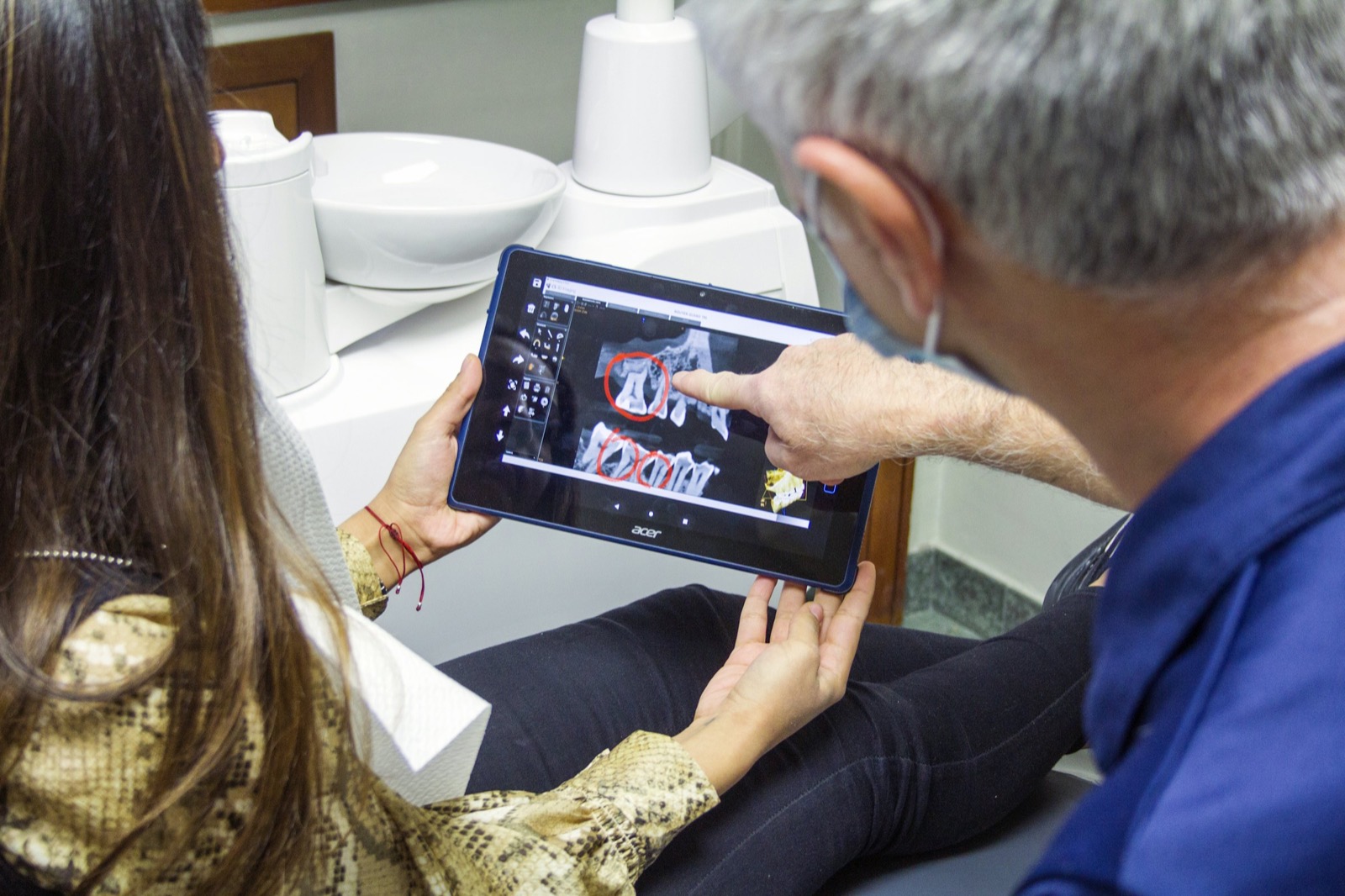 Dentist walking a patient through her dental images on a tablet