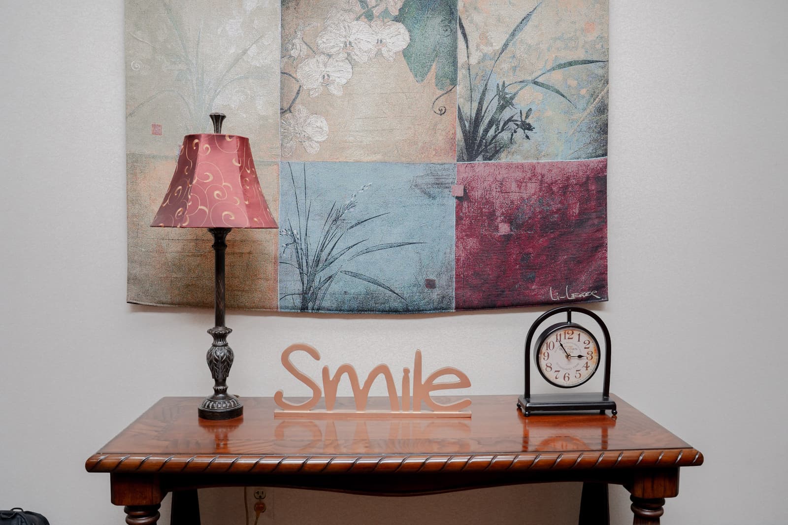 Entry table with a lamp, a clock, and a wooden “Smile” sign